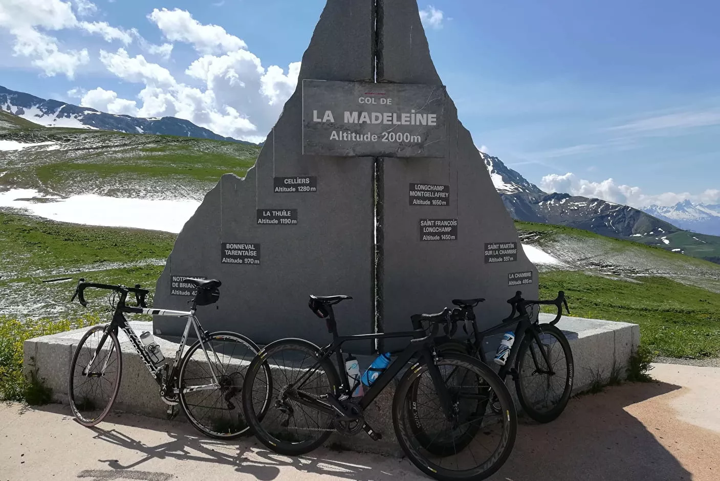 Stèle du col de la Madeleine à 1 993 m d'altitude avec les villages d'origine et leurs altitudes — 3 vélos posés au pied du monument